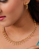 Woman wearing a gold necklace and earrings with a close-up of the jewelry.