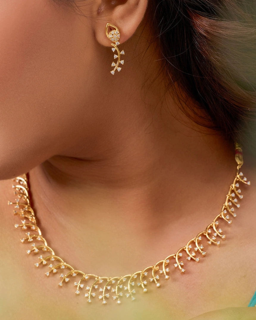 Close-up of a person wearing gold earrings and a necklace.