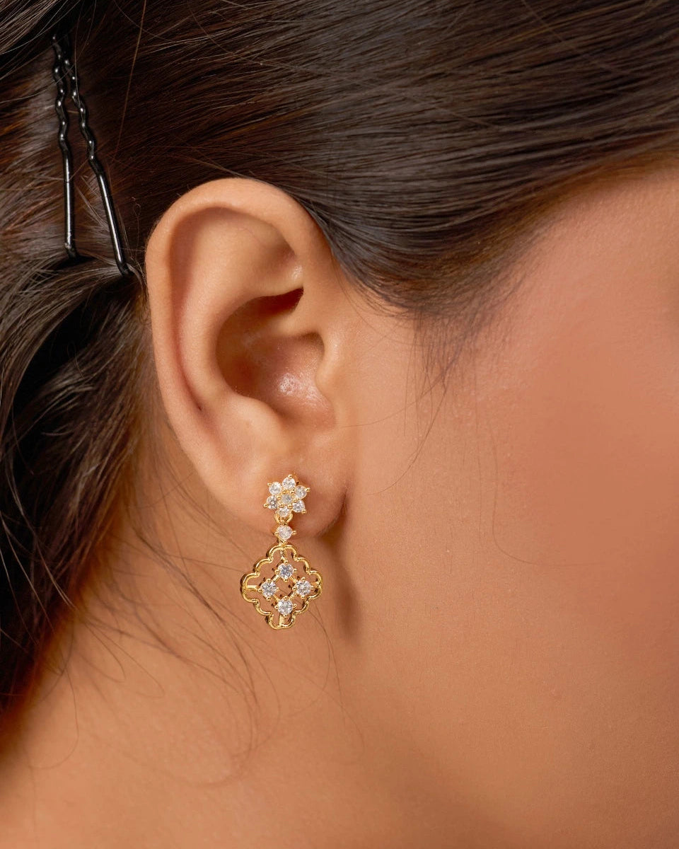 Close-up of an ear wearing a gold and diamond earring with hair partially pulled back.