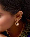 Close-up of a person wearing gold earrings and a necklace with intricate designs.