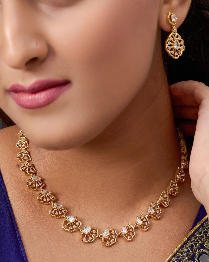 Woman wearing a gold necklace and earrings, with a close-up on the jewelry.