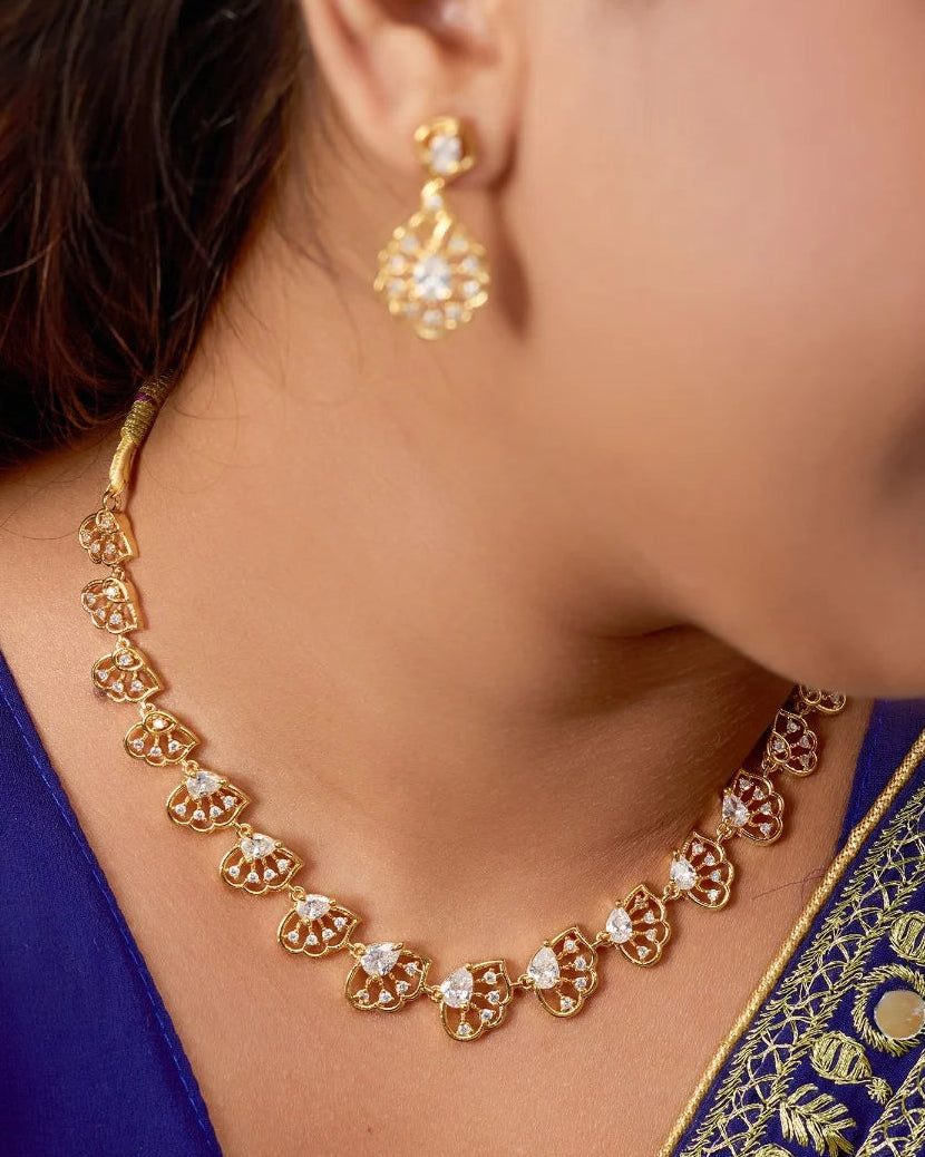 Woman wearing gold necklace and earrings with a blue saree