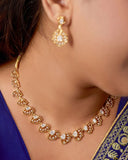 Woman wearing gold necklace and earrings with a blue saree