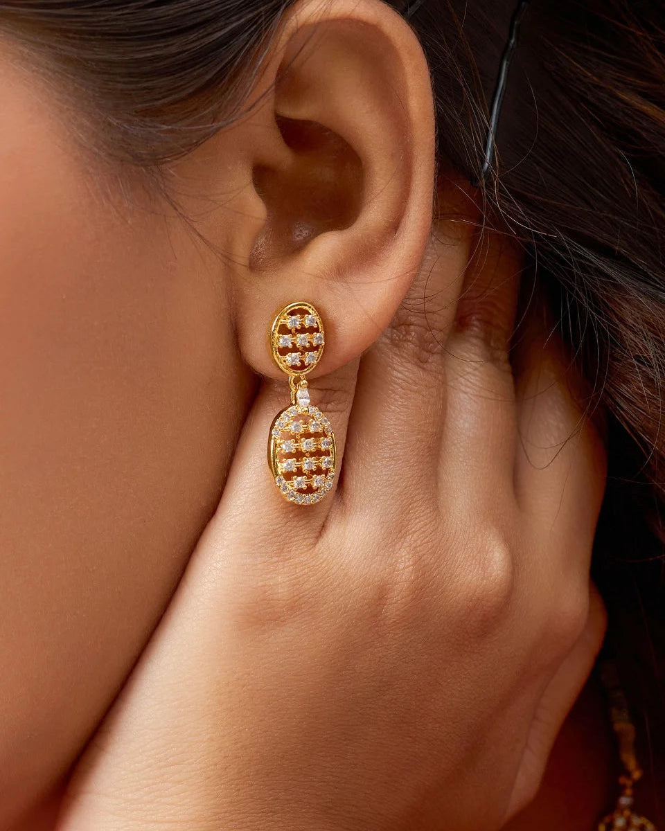 Close-up of a person wearing gold earrings with intricate designs.
