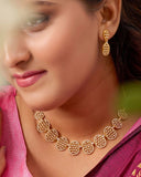 Woman wearing gold necklace and earrings with a blurred background