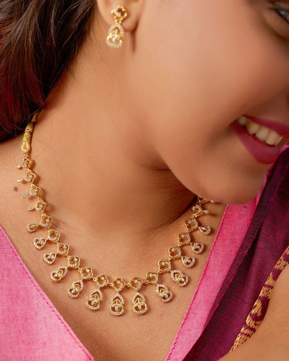 Woman wearing a gold necklace and earrings with a pink blouse