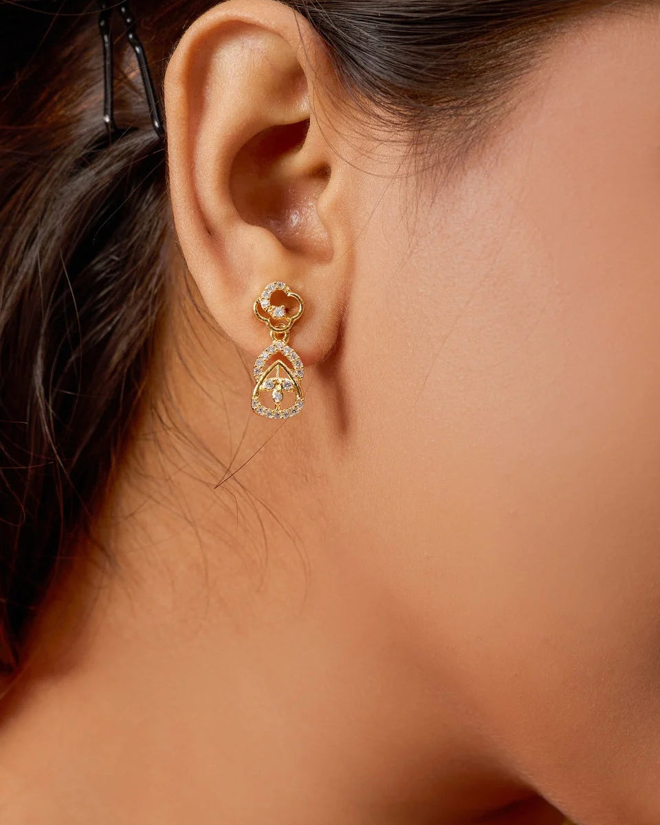 Close-up of a person wearing gold earrings with a blurred background