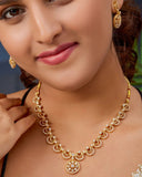 Woman wearing a gold necklace and earrings with a blurred background