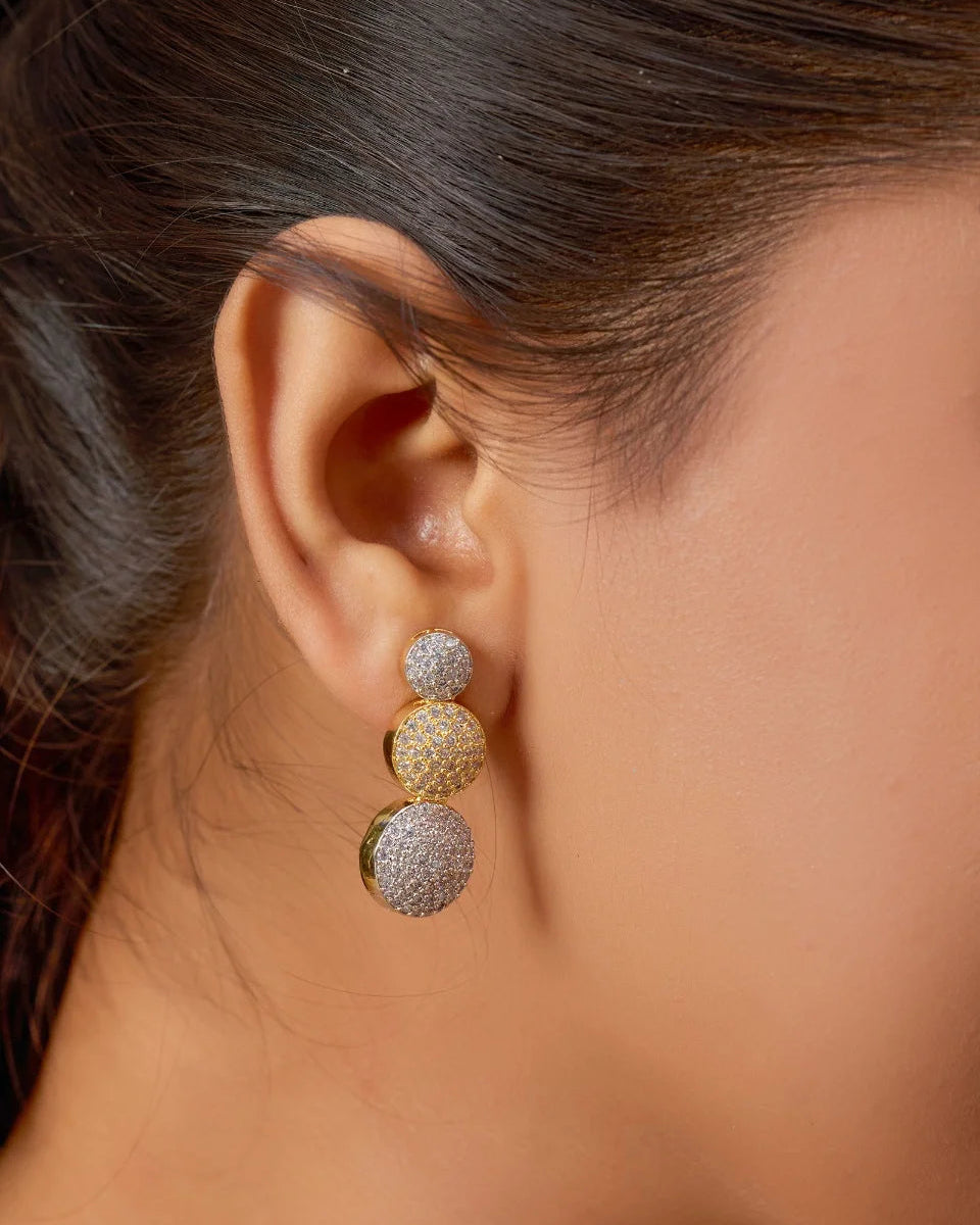 Close-up of a person wearing gold and silver spherical earrings.