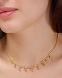 Gold necklace with dangling beads worn by a person