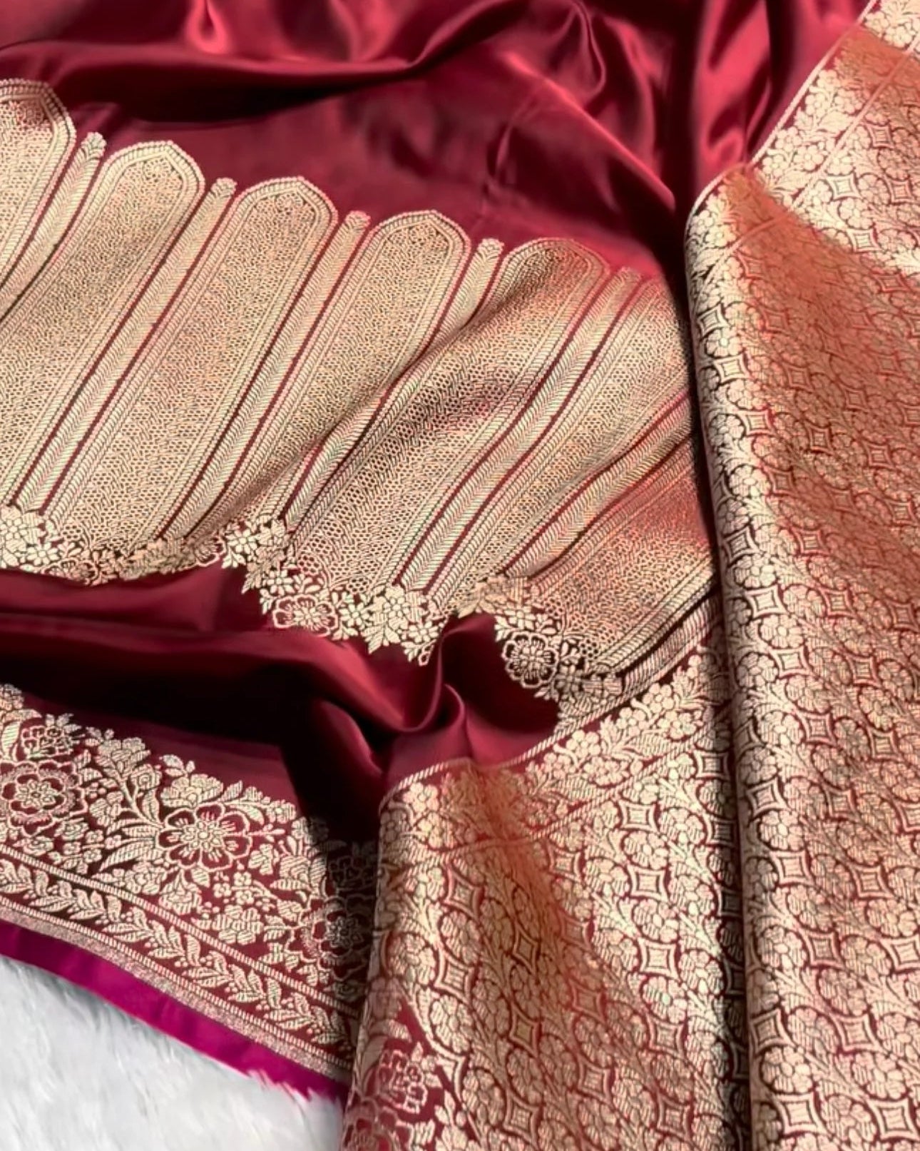 a close-up of a richly textured red and gold banarasi silk saree, showcasing the deep red body, the ornate gold zari brocade border, and the fine gold woven pattern on the pallu.