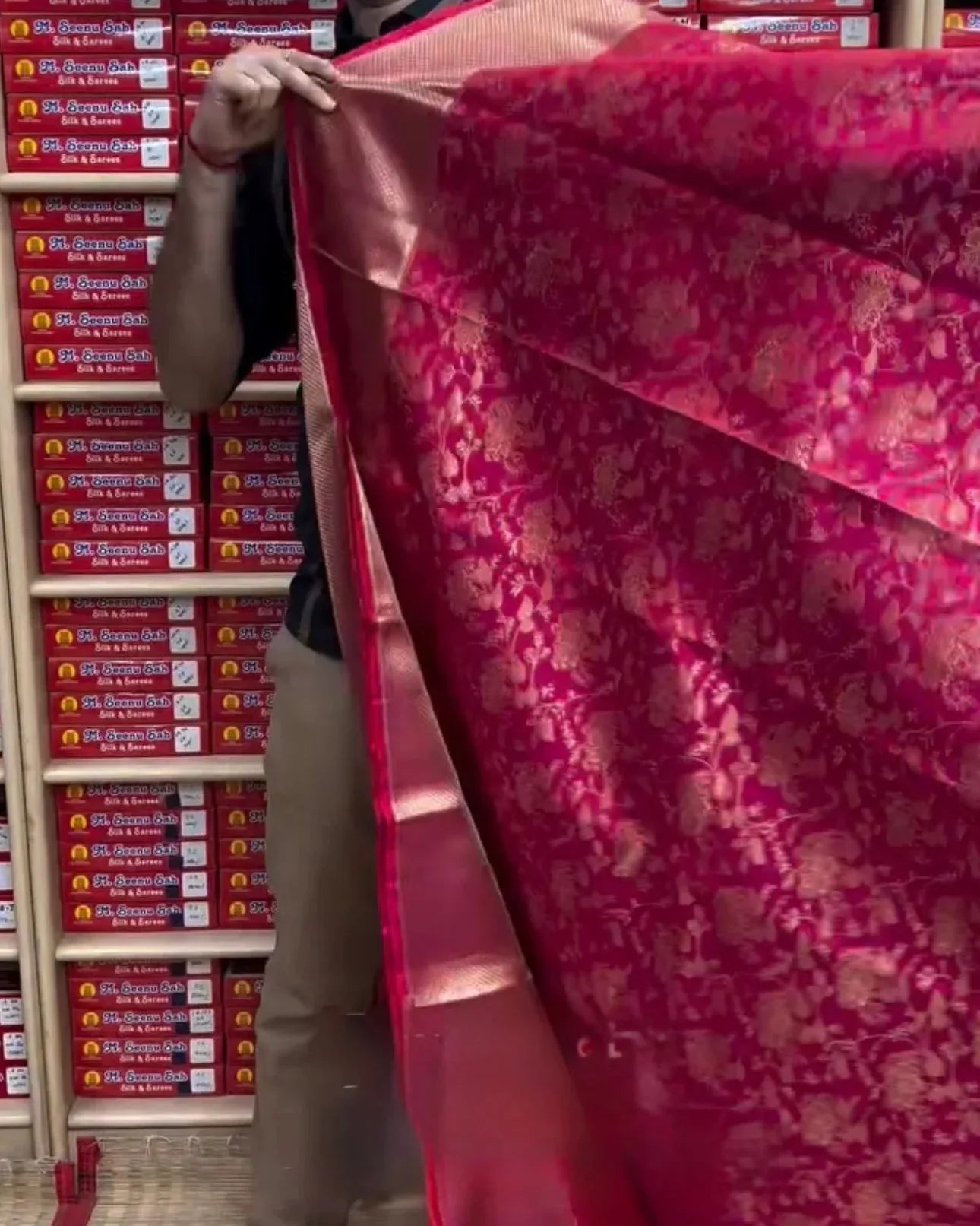 Person holding a large red fabric in front of stacked boxes.