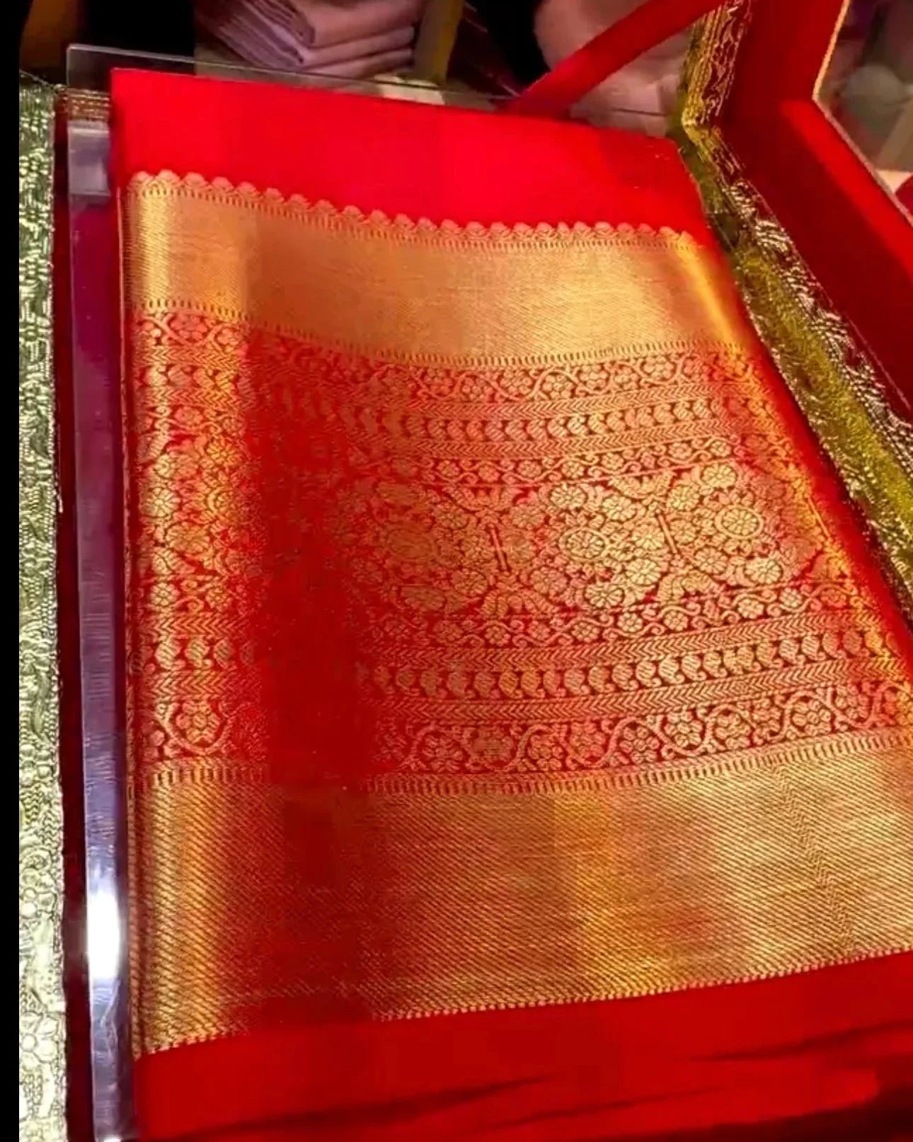 red and gold saree with intricate patterns in a decorative box