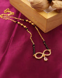 Gold necklace with black beads on a purple fabric background