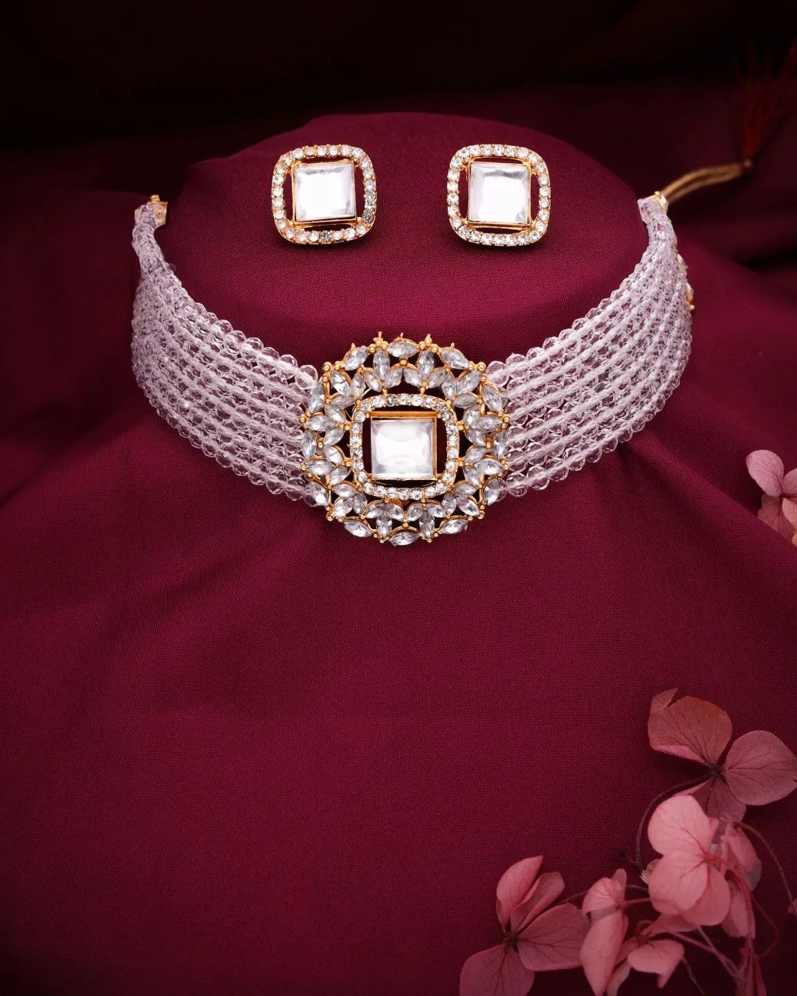 Jewelry set with a choker and earrings on a maroon fabric background